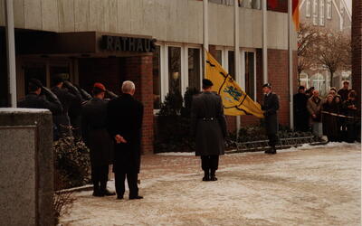 Soldaten salutieren beim feierlichen Einholen der Flagge vor dem Rathaus in Schwarzenbek, während Zuschauer zusehen.