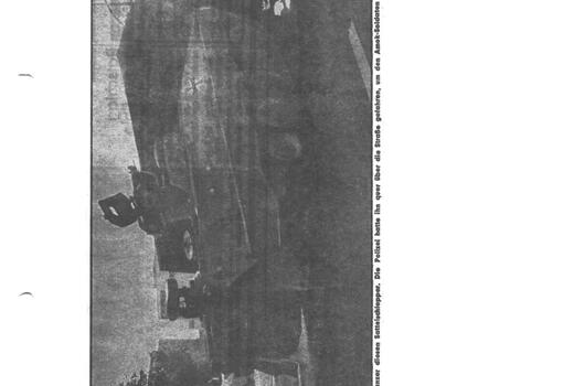 Ein Schützenpanzer Marder steht schräg auf der Straße, während eine Person in Eile daran vorbeiläuft.
