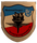 Wappen der Heeresflieger Versorgungsstaffel 65 mit Symbolen für Technik und Logistik vor einem rot-blau-weißen Hintergrund.