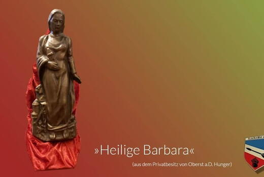 Die Statue der Heiligen Barbara steht auf rotem Stoff vor einem farbigen Hintergrund, mit einem Wappen unten rechts.