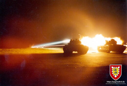 Zwei Panzer schießen bei Nacht mit leuchtendem Feuerstoß auf einem Übungsgelände.