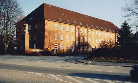 Die Bismarck-Kaserne von 1995 zeigt das geschlossene Haupttor vor einem großen, alten Backsteingebäude.