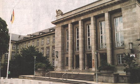 Ein historisches Gebäude mit Säulen und einer deutschen Flagge auf der Sophienterrasse an einem bewölkten Tag.