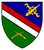Ein Wappen zeigt gekreuzte Werkzeuge und Gewehre auf blau-grünem Grund mit roten und weißen Streifen.