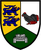 Ein Wappen zeigt zwei blaue Löwen, einen roten Hahn und einen grauen Panzer auf gelbem, weißem und grünem Hintergrund.