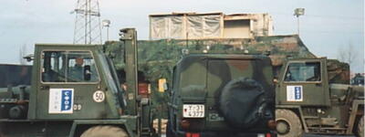 Zwei Militärfahrzeuge der SFOR-Umschlaggerätegruppe stehen 1997/98 auf einem Truppenstützpunkt nebeneinander.