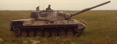 Ein Leopard-1-Panzer fährt 1982 über eine weite Wiese, während ein Soldat aus der Luke schaut.