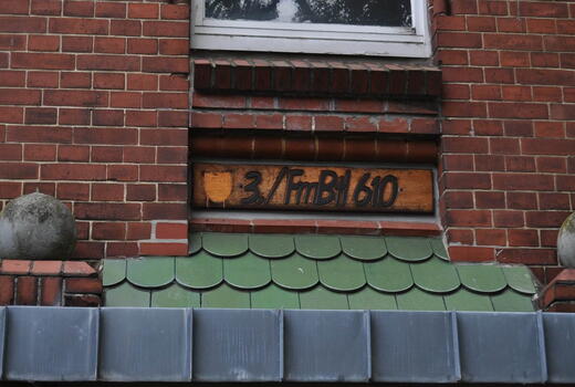 Ein Holzschild mit der Aufschrift "3./FmBtl 610" ist in eine rote Ziegelwand der Eider Kaserne eingelassen.