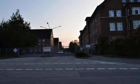 Das Eingangstor der Trave-Kaserne 2009 zeigt Gebäude bei Sonnenuntergang im Hintergrund.
