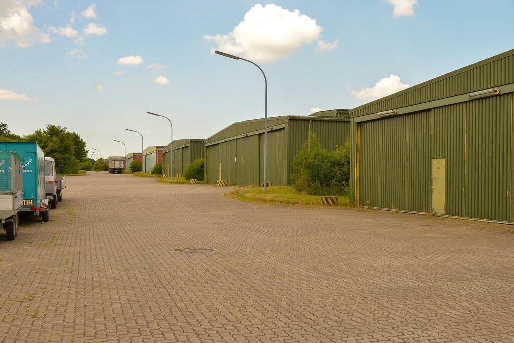 Eine Reihe grüner Lagerhallen in der Dithmarsen-Kaserne, umgeben von gepflasterten Wegen und vereinzeltem Grün.