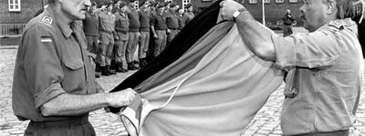Zwei Soldaten falten feierlich eine Flagge vor einer Reihe von Kameraden auf einem Kasernenhof.