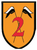 Ein Wappen mit einer roten Zahl 2 und zwei gekreuzten Fahnen auf orangem Hintergrund repräsentiert die 2. Kompanie.
