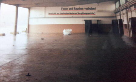 Ein leerer, weitläufiger Raum mit einem Warnschild an der Wand, das Feuer und Rauchen untersagt.