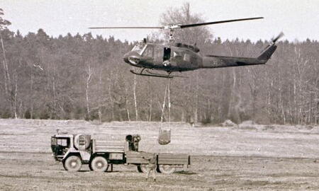 Ein Hubschrauber transportiert mit einem Seil eine Ladung über ein Feld in Boostedt während einer militärischen Übung.