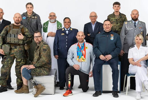 Eine Gruppe von Personen in verschiedenen Uniformen und Outfits posiert vor einem weißen Hintergrund.