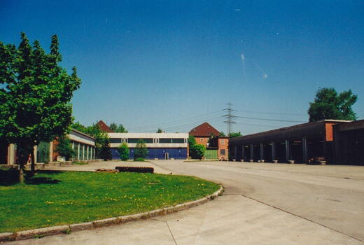 Ein sonniger Tag auf dem Gelände der Bismarck-Kaserne 1994 mit Gebäuden, Grünflächen und einem klaren blauen Himmel.