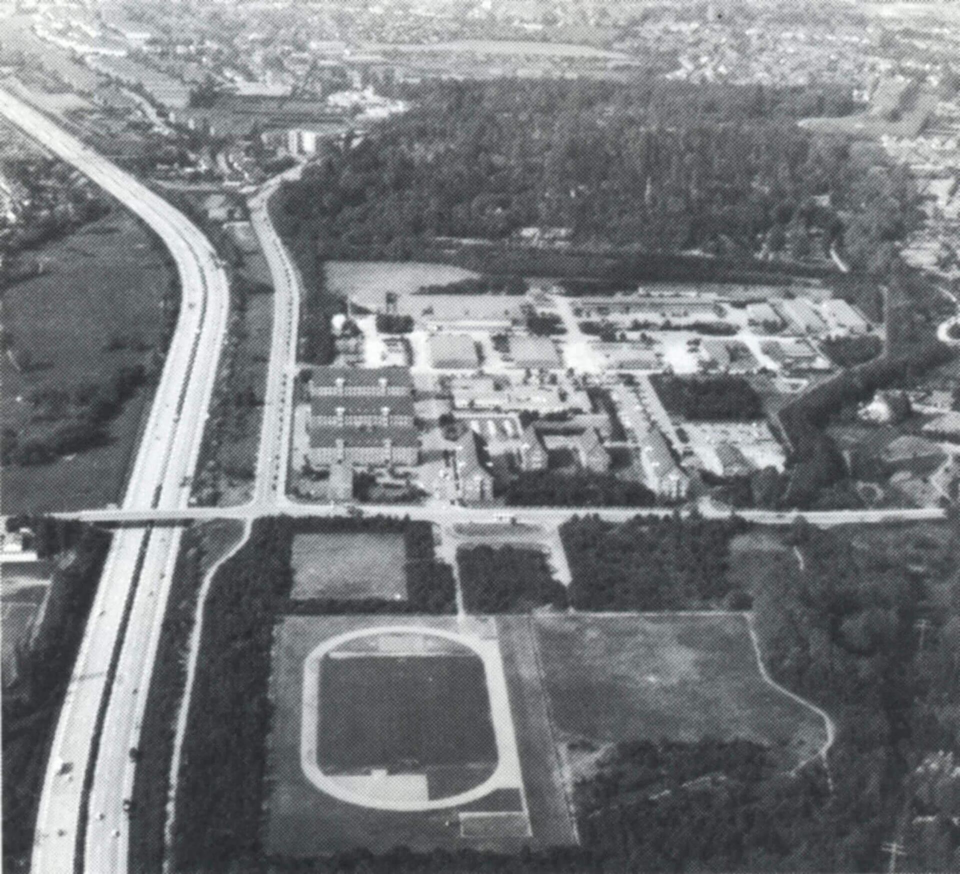 Luftaufnahme der Trave-Kaserne mit angrenzender Autobahn und Sportplatz, umgeben von Wald und städtischer Infrastruktur.