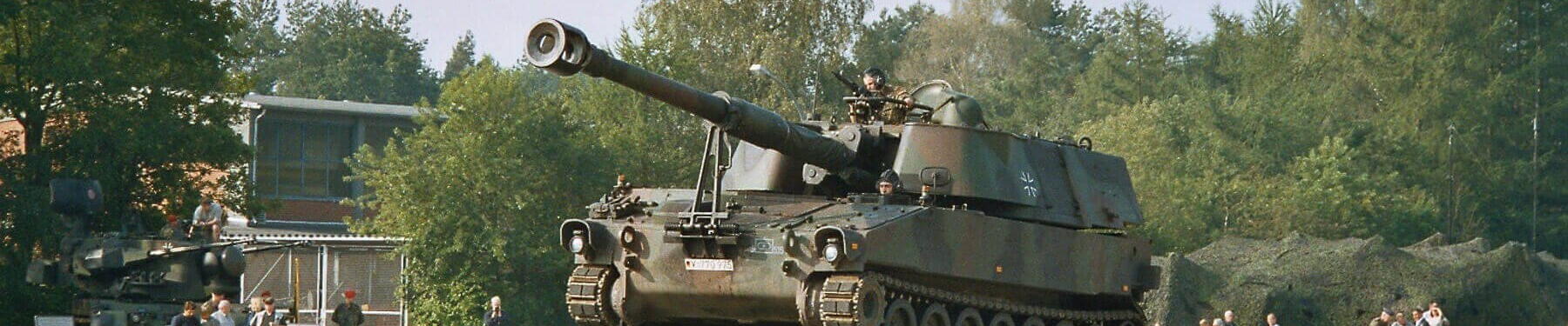 Ein Panzerhaubitze M109 A3 rollt 2004 in Boostedt eine Rampe hinauf, umgeben von Zuschauern und Bäumen.
