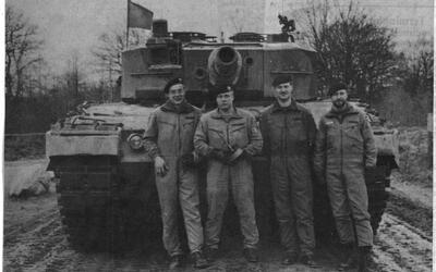 Vier Soldaten posieren vor einem Kampfpanzer auf einem Übungsplatz, begleitet von dem Titel "Letzter Schuss".