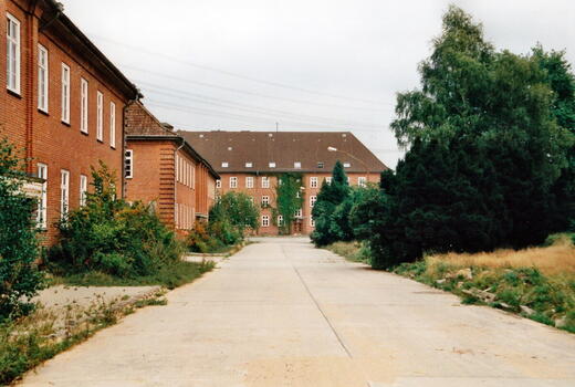 Ein leerer Hof in der Bismarck-Kaserne 1996, umgeben von roten Backsteingebäuden und dichtem Grün.