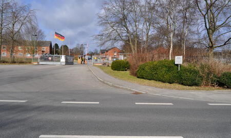 Der Eingang zur Schill-Kaserne 2012 zeigt ein geschlossenes Tor mit wehender deutscher Flagge und kahlen Bäumen im Hintergrund.