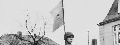 Soldaten salutieren aus einem vorbeifahrenden Panzer während einer Parade in Bad Segeberg, begleitet von einer Fahne.