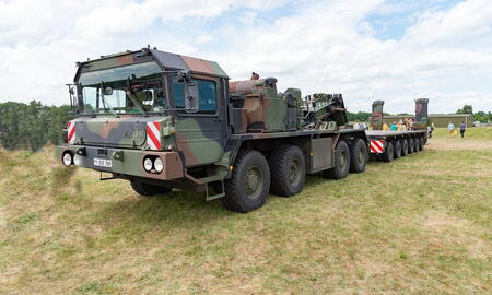 Ein militärischer Schwerlasttransporter steht imposant auf einer Wiese beim Tag der Bundeswehr 2016, umgeben von Besuchern.