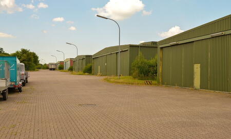 Eine Reihe grüner Lagerhallen in der Dithmarsen-Kaserne, umgeben von gepflasterten Wegen und vereinzeltem Grün.