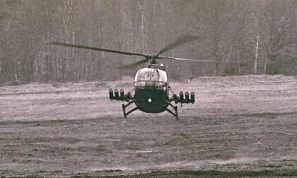 Ein Hubschrauber fliegt knapp über dem Boden in einem offenen Feld bei einer Übung in Boostedt im Jahr 1986.