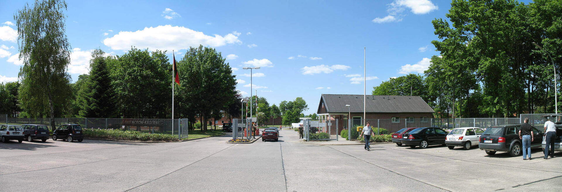 Das Haupttor der Liliencron-Kaserne zeigt parkende Autos und Besucher bei sonnigem Wetter im Jahr 2008.