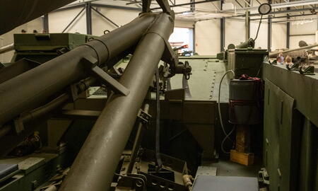 Ein großer militärischer Raketenwerfer ist in einer Halle ausgestellt, umgeben von Stahlkonstruktionen.