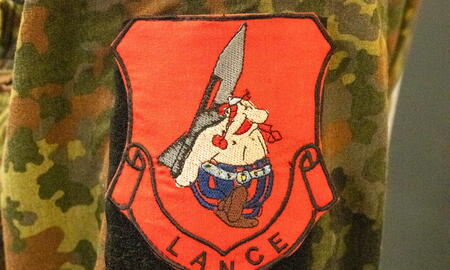 Ein Ärmel einer Tarnjacke zeigt das Abzeichen "Lance" und die deutsche Flagge darüber.