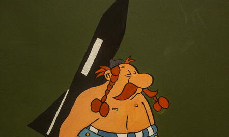 Ein Cartoon eines fröhlichen, kräftigen Kriegers mit einem großen Pfeil auf einer grünen Metalloberfläche.