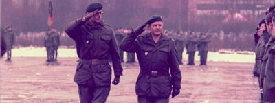 Zwei Offiziere salutieren während einer militärischen Übergabezeremonie auf einem nassen Exerzierplatz im Jahr 1985.