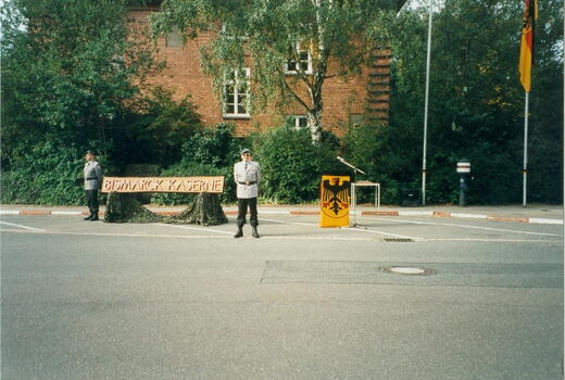 Zwei Soldaten stehen neben einem Schild mit der Aufschrift "Bismarck Kaserne" vor einem Backsteingebäude.