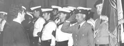 Marineoffiziere und Soldaten stehen in Formation, während ein Offizier salutiert, bei einer Fahnenbandverleihung 1983.