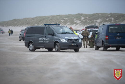 Ein Militärsicherheitsfahrzeug und Soldaten sind auf einem sandigen Küstenabschnitt im Einsatz.