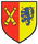 Ein Wappen zeigt gekreuzte Kanonenrohre auf rotem Grund und einen blauen Löwen mit roten Herzen auf gelbem Grund.