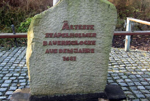 Ein Stein mit eingraviertem Text erinnert an die älteste Stapelholmer Bauernlocke aus dem Jahr 1681.