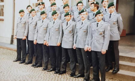 Eine Gruppe von Soldaten in Uniform posiert in zwei Reihen für ein Foto vor einem Gebäude beim Wettkampf 1980.